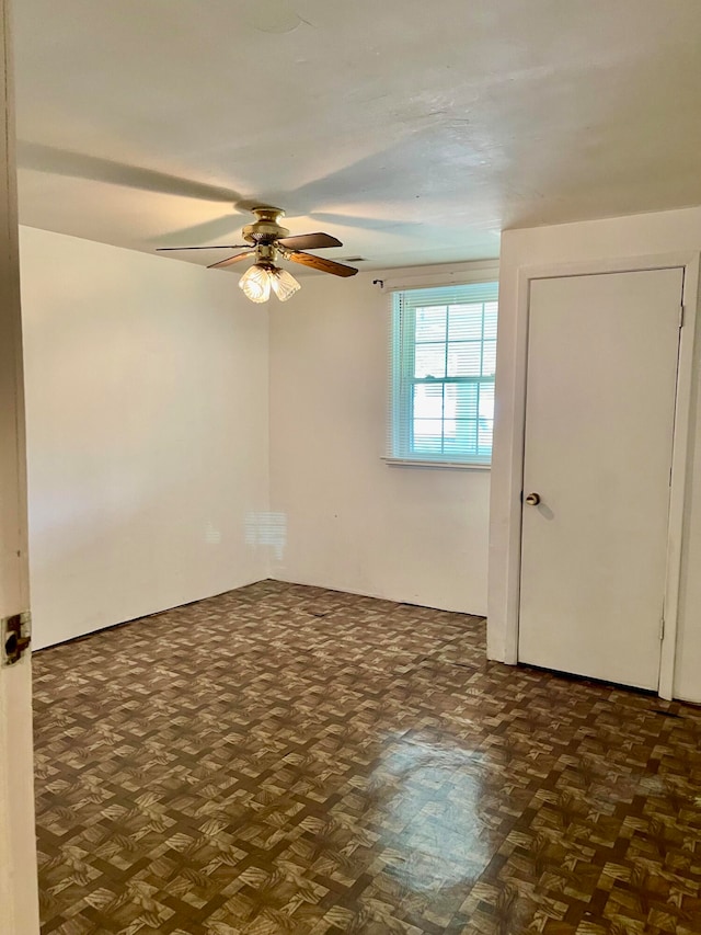 spare room with ceiling fan and dark parquet floors