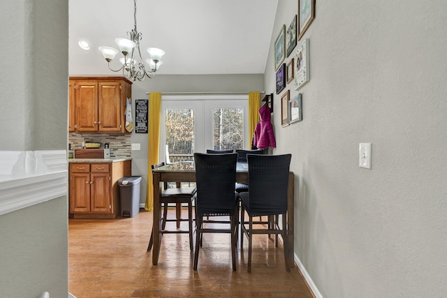 dining space featuring a chandelier, light wood-type flooring, french doors, and baseboards