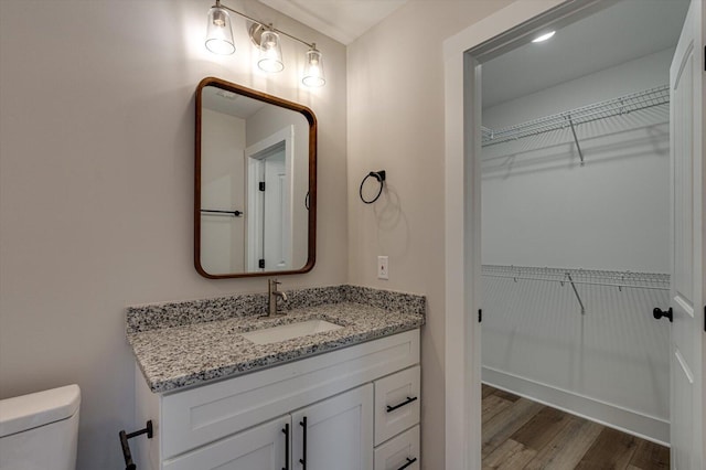 bathroom with wood-type flooring, vanity, and toilet