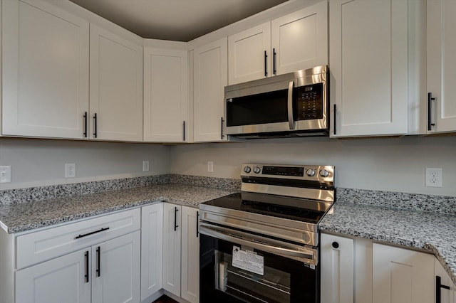 kitchen with white cabinetry, appliances with stainless steel finishes, and light stone counters