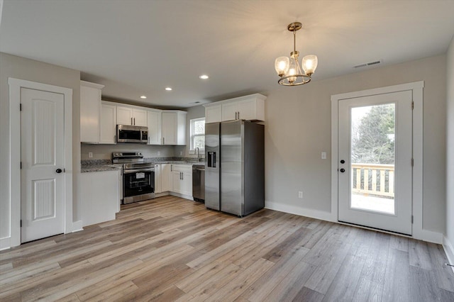 kitchen featuring decorative light fixtures, white cabinetry, sink, light hardwood / wood-style floors, and stainless steel appliances