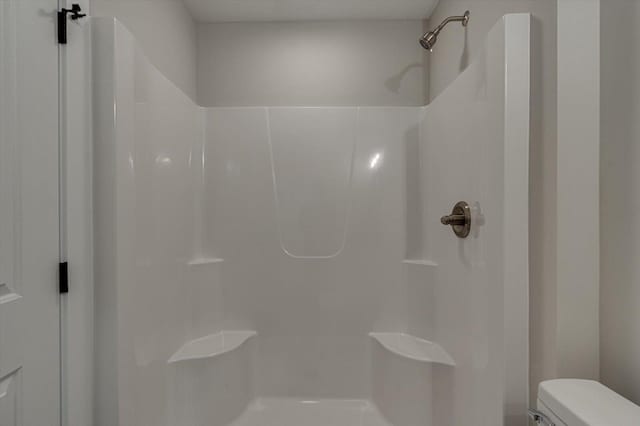 bathroom featuring walk in shower and toilet