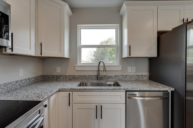 kitchen featuring sink, light stone countertops, white cabinets, and appliances with stainless steel finishes