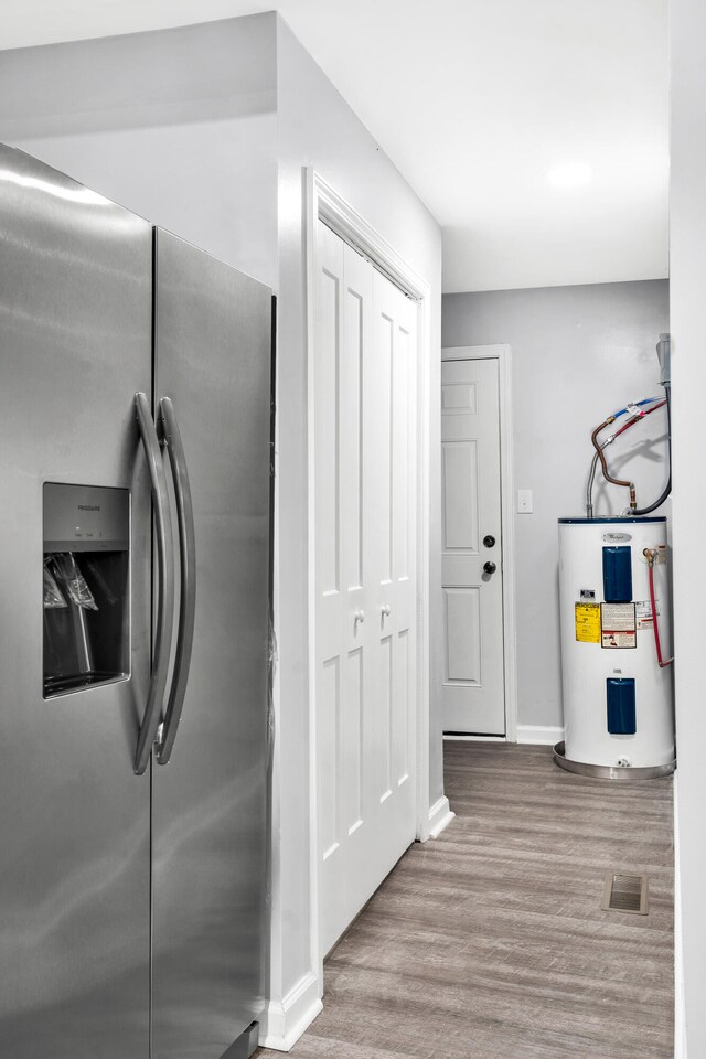 kitchen featuring stainless steel fridge, light hardwood / wood-style floors, and electric water heater