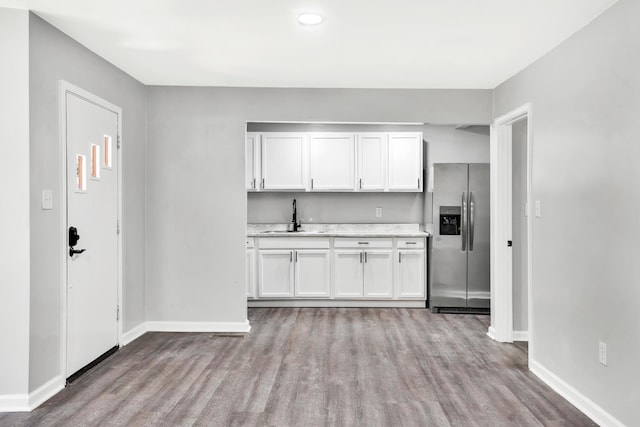 kitchen featuring stainless steel fridge, light wood-type flooring, white cabinetry, and sink