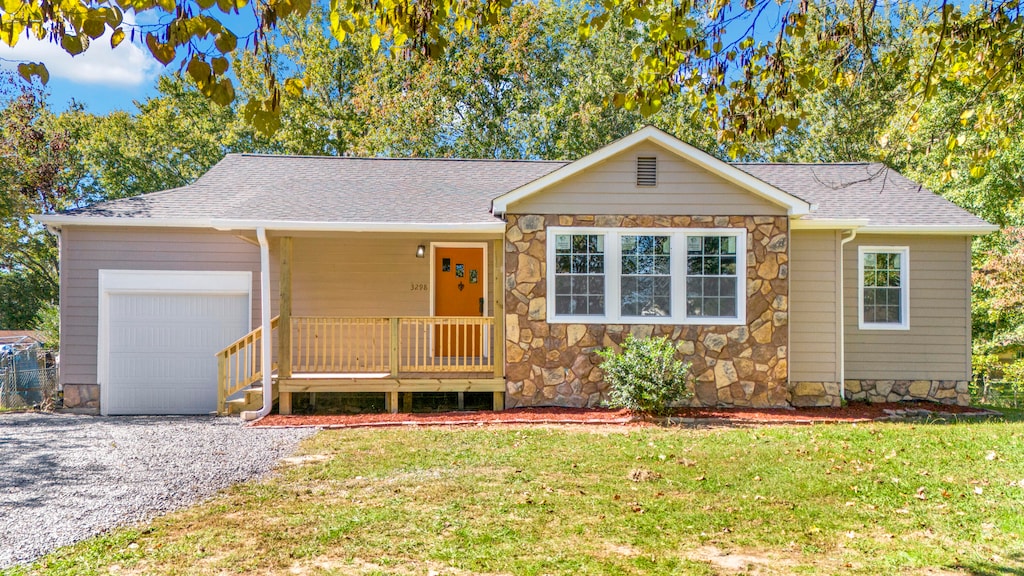 ranch-style home featuring a front yard, a porch, and a garage