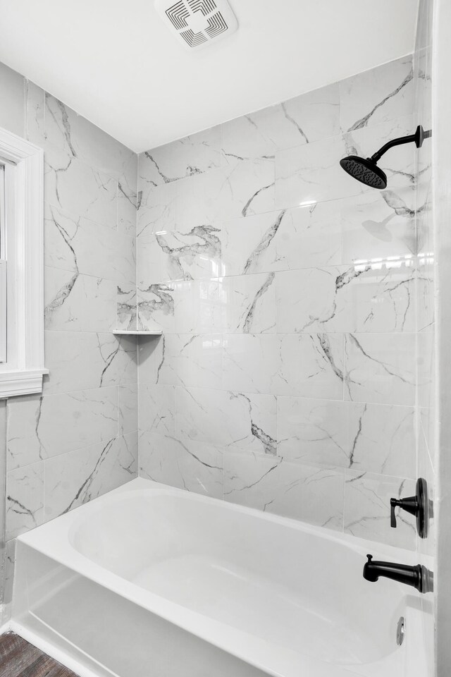 bathroom with hardwood / wood-style floors and tiled shower / bath