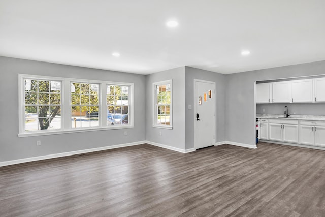 unfurnished living room featuring plenty of natural light, dark wood-type flooring, and sink