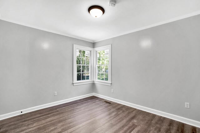 empty room with dark hardwood / wood-style flooring and ornamental molding