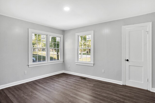 unfurnished room with ornamental molding and dark wood-type flooring