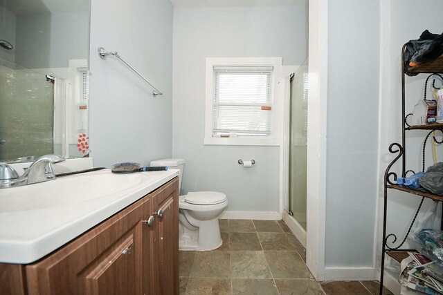 bathroom featuring vanity, a shower with shower door, and toilet