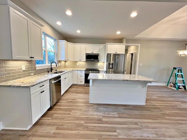 kitchen with stainless steel appliances, sink, a center island, light hardwood / wood-style floors, and white cabinetry