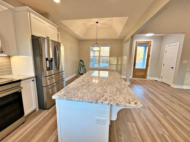 kitchen featuring white cabinetry, an inviting chandelier, a tray ceiling, a kitchen island, and appliances with stainless steel finishes