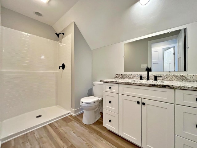 bathroom with walk in shower, vanity, hardwood / wood-style flooring, toilet, and lofted ceiling