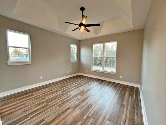 empty room featuring a tray ceiling, ceiling fan, and hardwood / wood-style flooring