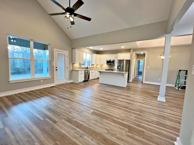 kitchen with ceiling fan, high vaulted ceiling, appliances with stainless steel finishes, white cabinets, and light wood-type flooring