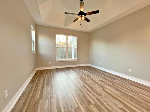 unfurnished room with a tray ceiling, light hardwood / wood-style flooring, and ceiling fan