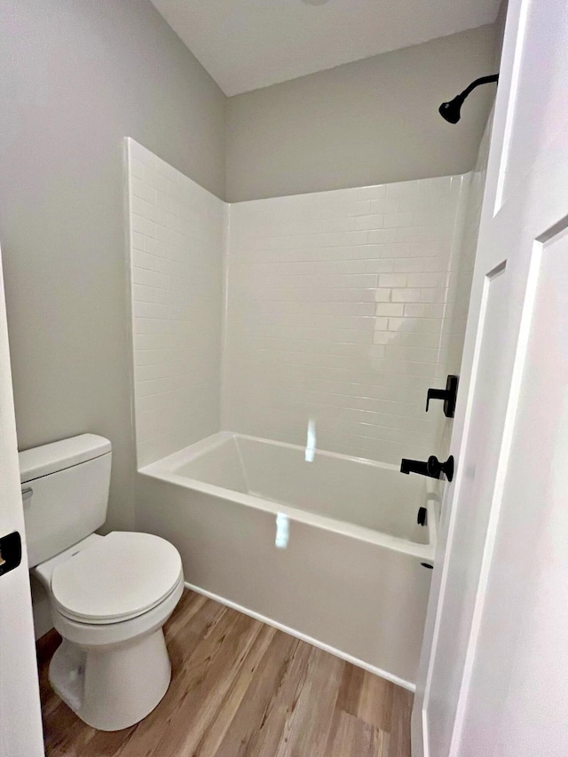 bathroom with  shower combination, hardwood / wood-style flooring, and toilet