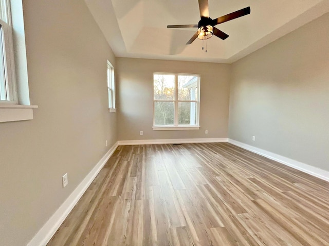 unfurnished room featuring ceiling fan, a raised ceiling, and light hardwood / wood-style flooring