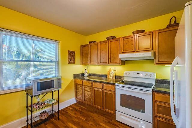 kitchen with dark stone countertops, dark wood-type flooring, and white appliances