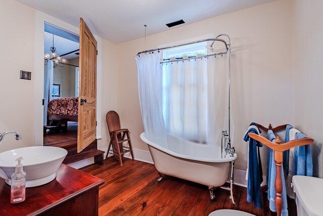 bathroom with hardwood / wood-style flooring, a notable chandelier, a bathtub, and sink