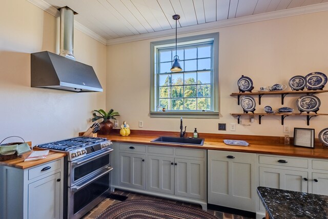 kitchen featuring butcher block countertops, double oven range, wall chimney exhaust hood, and sink