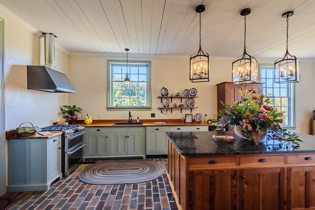 kitchen with pendant lighting, double oven range, wall chimney range hood, and sink