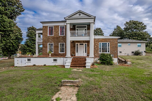 greek revival house featuring a front yard, a porch, and a balcony