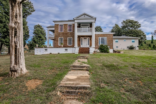 greek revival house featuring a balcony and a front lawn