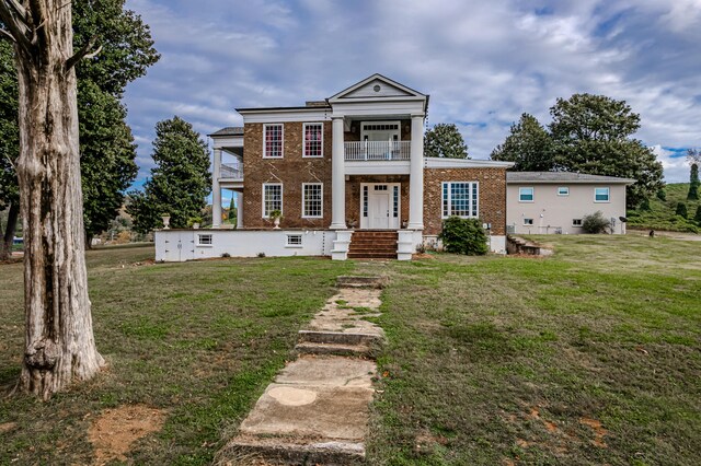 greek revival house with a balcony and a front yard