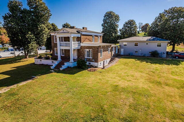 rear view of house with a yard and a balcony