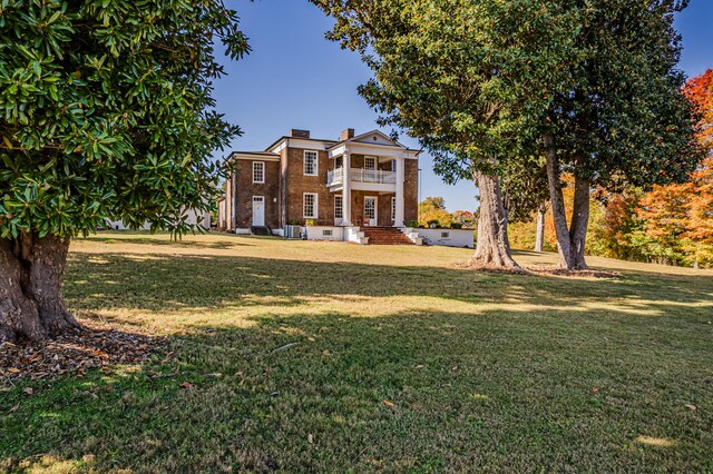 neoclassical / greek revival house featuring a balcony and a front lawn