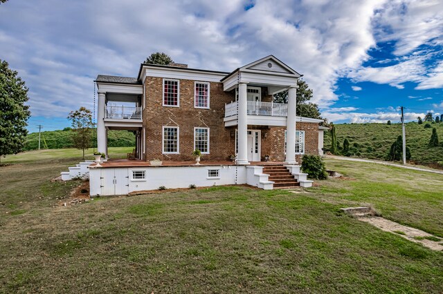 neoclassical home featuring a balcony and a front yard