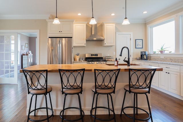 kitchen featuring stainless steel appliances, wall chimney range hood, a center island with sink, white cabinets, and dark hardwood / wood-style floors