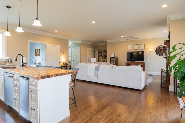 kitchen with wood counters, dark wood-type flooring, sink, decorative light fixtures, and white cabinets