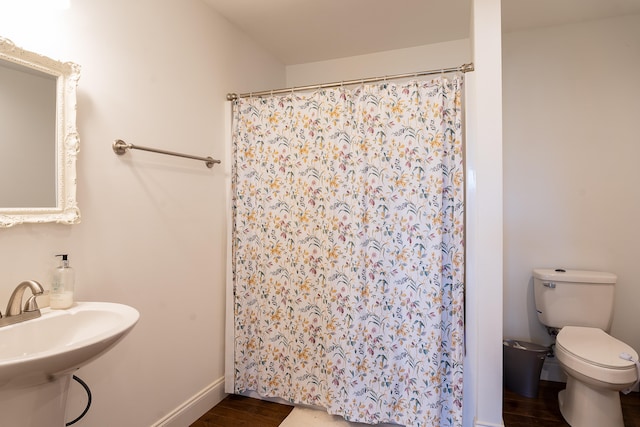 bathroom featuring a shower with shower curtain, hardwood / wood-style floors, toilet, and sink