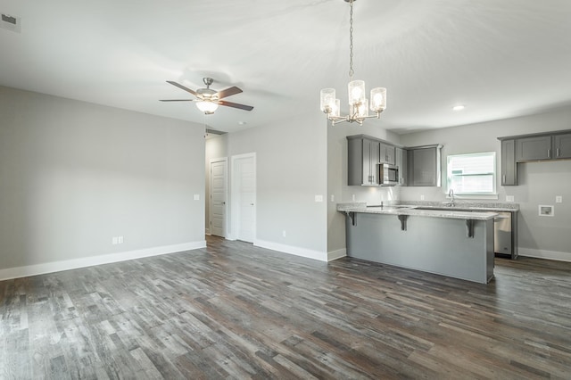 kitchen with ceiling fan with notable chandelier, gray cabinets, kitchen peninsula, and dark wood-type flooring