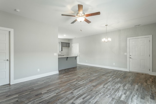 unfurnished living room with dark hardwood / wood-style floors and ceiling fan with notable chandelier