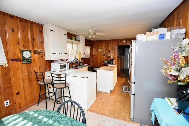 kitchen featuring stainless steel fridge, ceiling fan, a center island, white cabinets, and sink