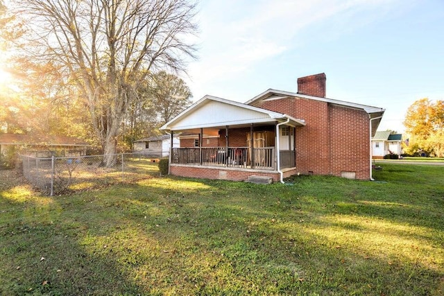 back of house with covered porch and a lawn