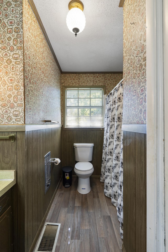 bathroom featuring ornamental molding, vanity, a textured ceiling, wooden walls, and hardwood / wood-style flooring