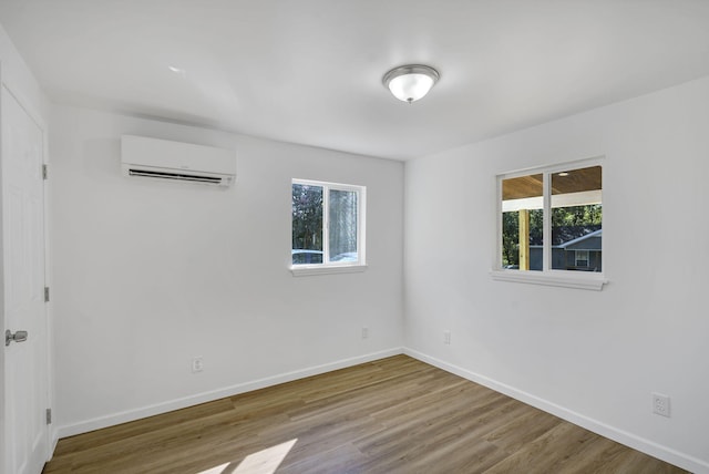 spare room with a wall mounted air conditioner, hardwood / wood-style flooring, and a wealth of natural light