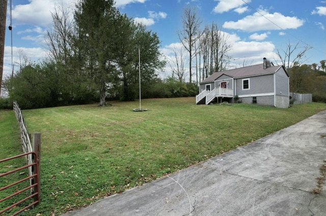 view of yard featuring concrete driveway and fence