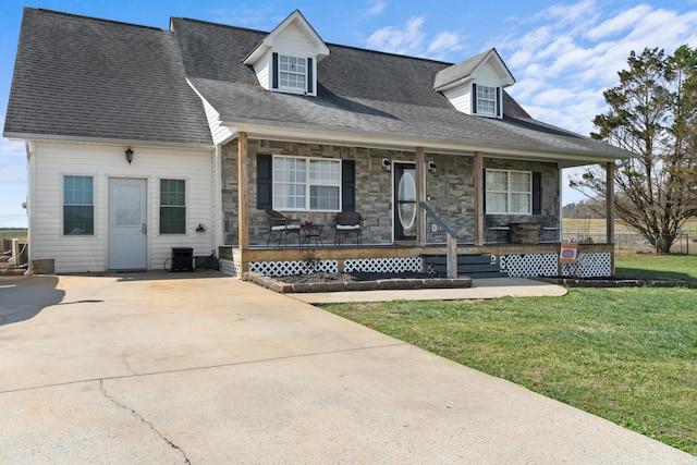 cape cod-style house with a shingled roof, a front lawn, a porch, stone siding, and driveway