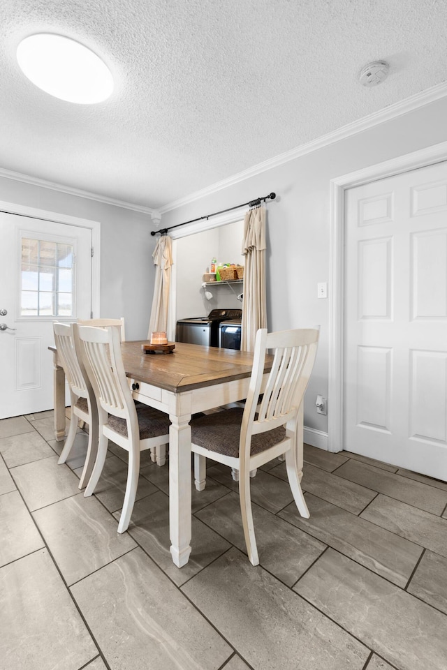 dining space with a textured ceiling, crown molding, and washing machine and clothes dryer