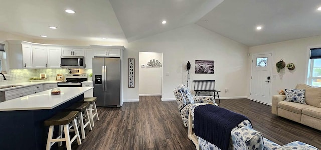 kitchen with sink, a kitchen breakfast bar, stainless steel appliances, a center island, and white cabinets