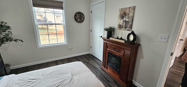 bedroom with multiple windows and dark wood-type flooring