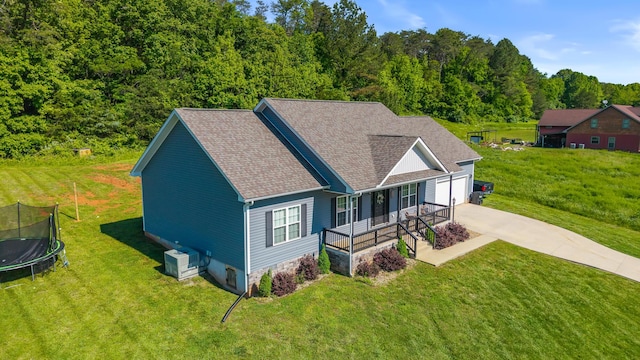 123 Tommy Loop, Sweetwater, TN 37874 - rear view of property featuring a trampoline, driveway, a yard, an attached garage, and a shingled roof