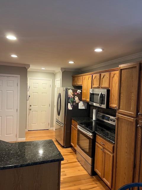 kitchen featuring dark stone countertops, light hardwood / wood-style floors, crown molding, and stainless steel appliances