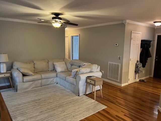 living room featuring ceiling fan, wood-type flooring, and ornamental molding